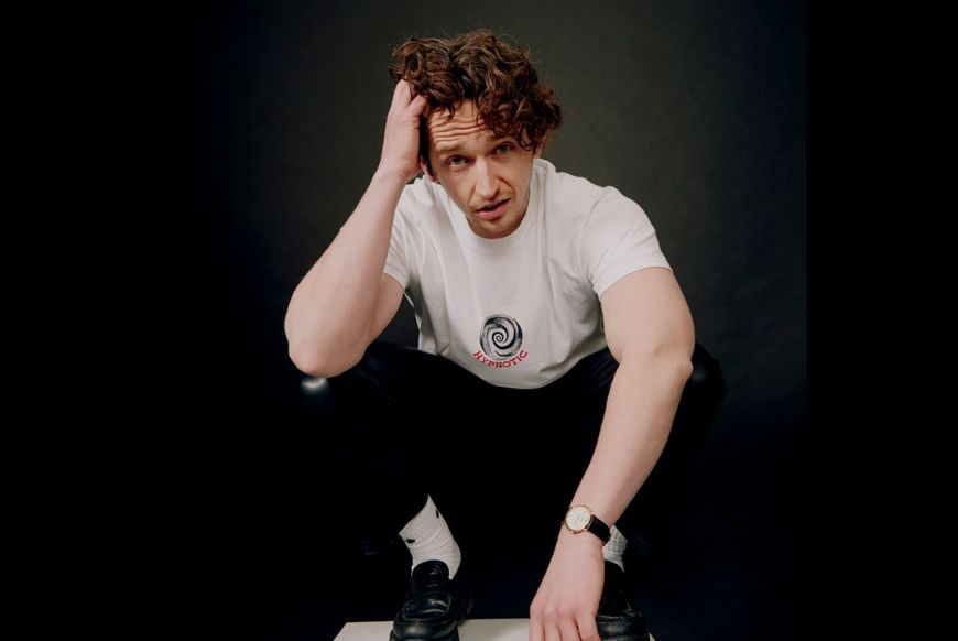 man sits on a white box with a black background